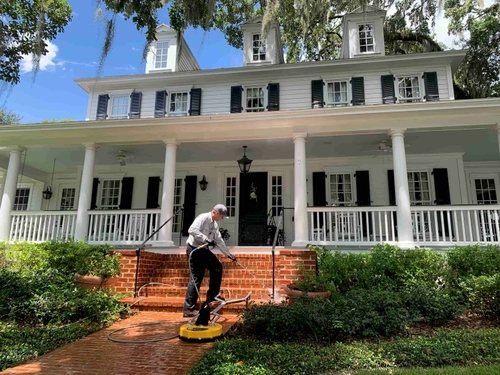 Pressure washing a brick walkway and front porch