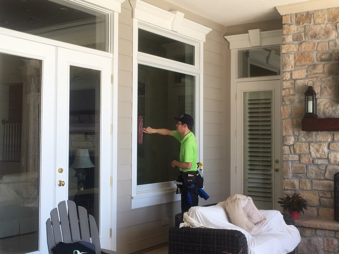 Window cleaning technician detailing glass by a doorway